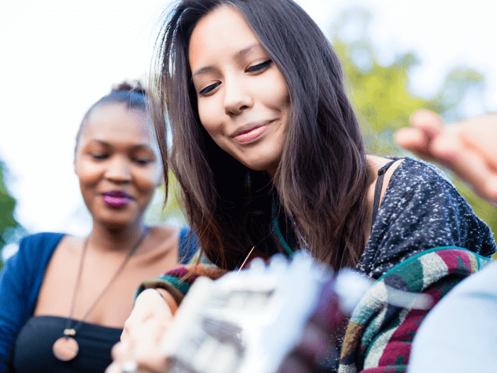 Young woman playing acoustic guitar with friends in a field.